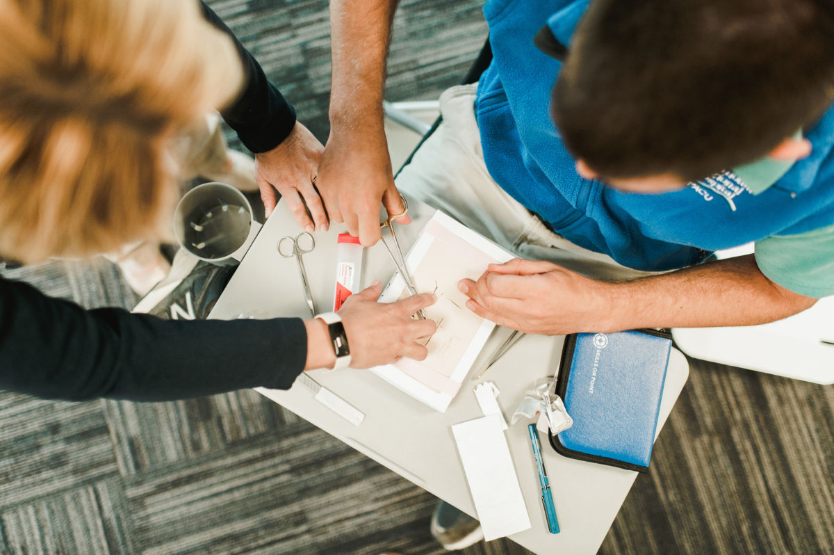 professor teaches suturing to a nursing student