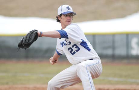A baseball player wearing a white and blue uniform with the number 23 is in the process of throwing a pitch, perhaps during one of the conference championships. Saint Joseph's College of Maine