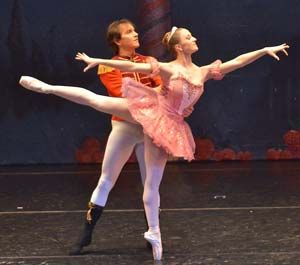 Two ballet dancers from the Maine State Ballet perform on stage. The female dancer, in a pink tutu, strikes an arabesque pose while the male dancer stands behind her in a red and white costume. This captivating performance adds a magical touch to the holidays for students and families alike. Saint Joseph's College of Maine