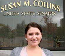 A woman stands in front of a window with the text "Susan M. Collins, United States Senator" written on it, representing a figure respected across both red states and blue states. Saint Joseph's College of Maine