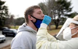 Photo taken by Brianna Soukup of the Portland Press Herald of SJC's health director testing student for covid-19 before sending students home to finish out the semester.