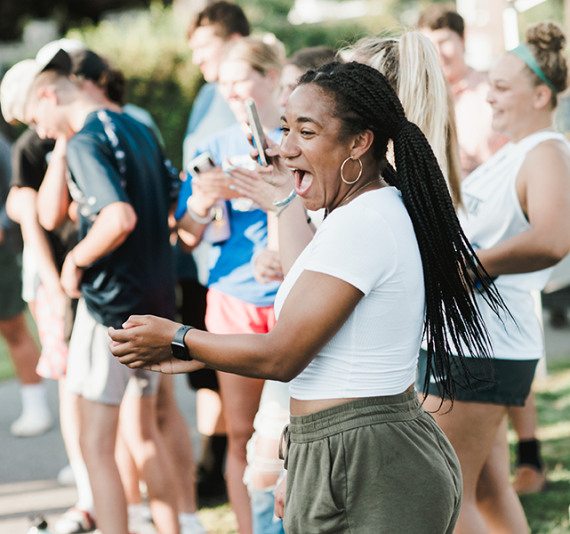 Student cheering her classmates on during a game at Welcome Weekend.