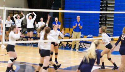 On the sidelines, Jon Roberts coaches during a volleyball match