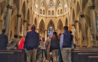 Holy Year Of Mercy Pilgrimage 1 A group of people on a pilgrimage stand inside a large church with high arched ceilings and stained glass windows, marking the Holy Year of Mercy. Saint Joseph's College of Maine