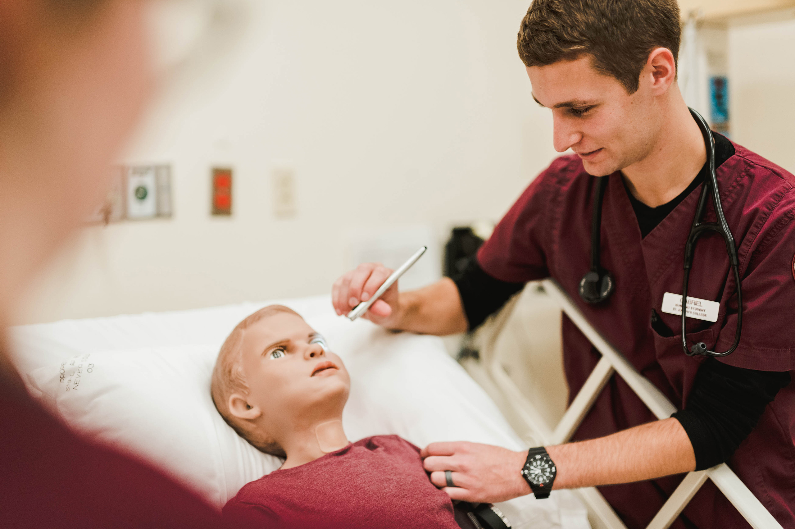 male nursing student examines simulation boy